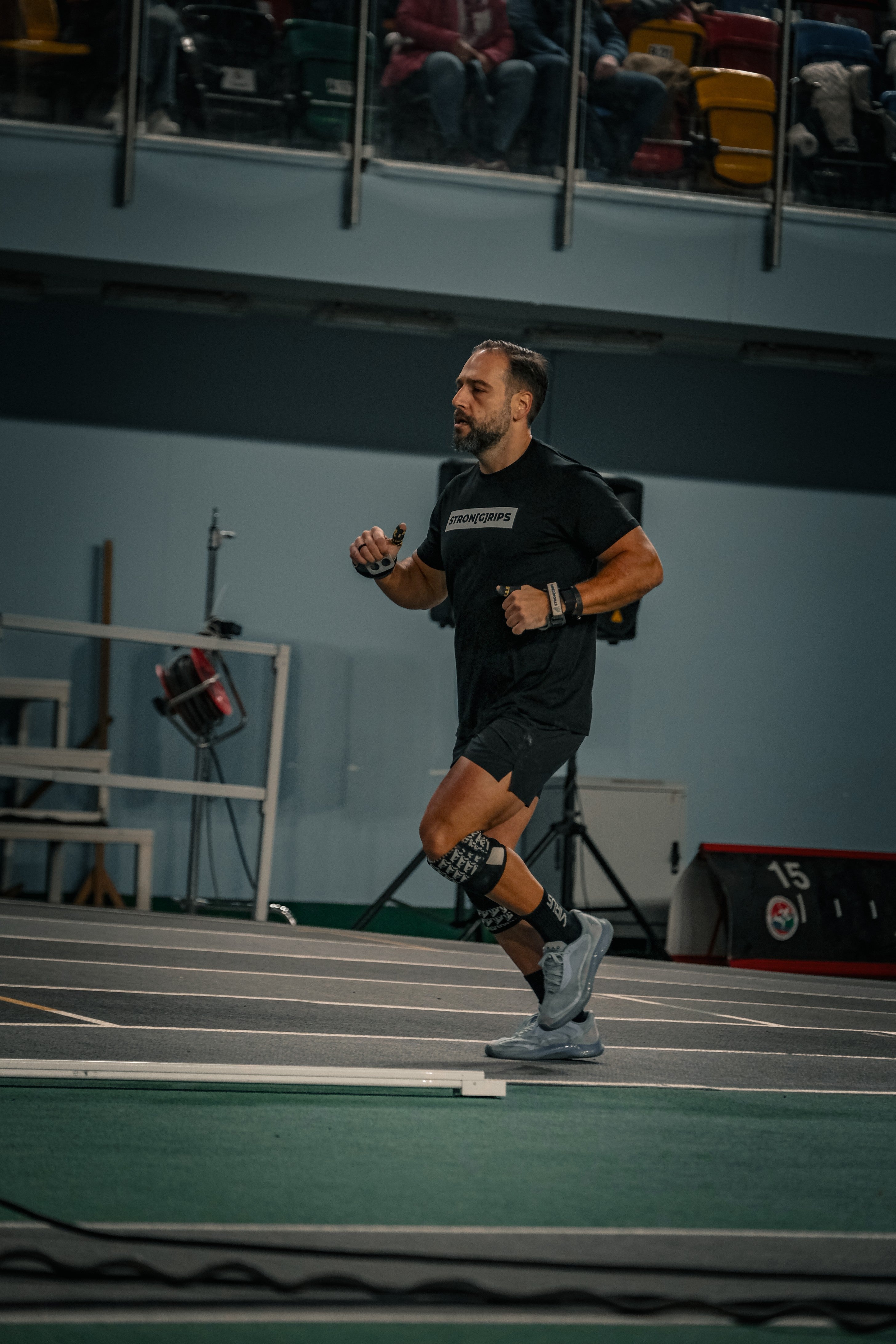 A running athlete wearing StronGrips knee sleeves, t-shirt, and hand grips. Focused on endurance and performance training.